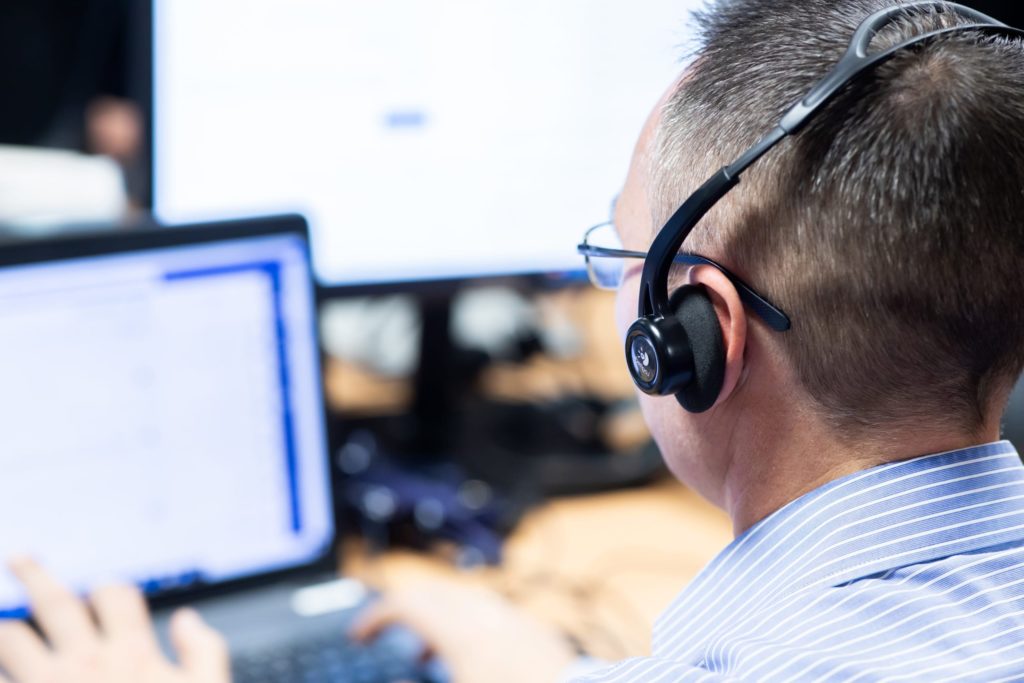 customer support worker with headphones in front of computer